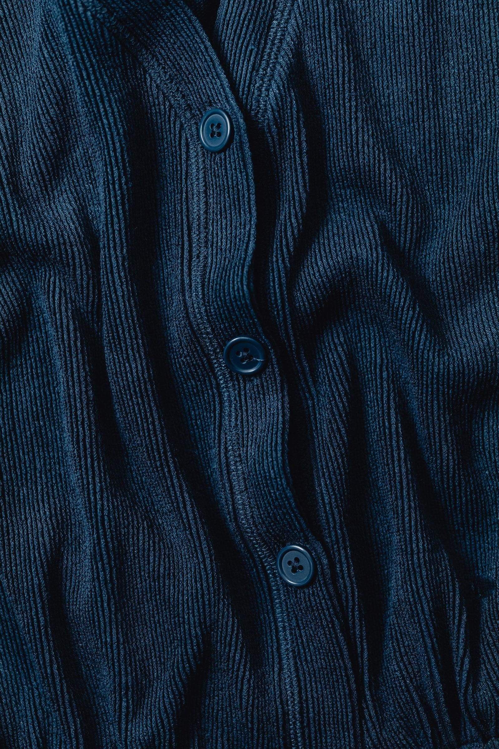 Blue ribbed garment fabric with a button placket.