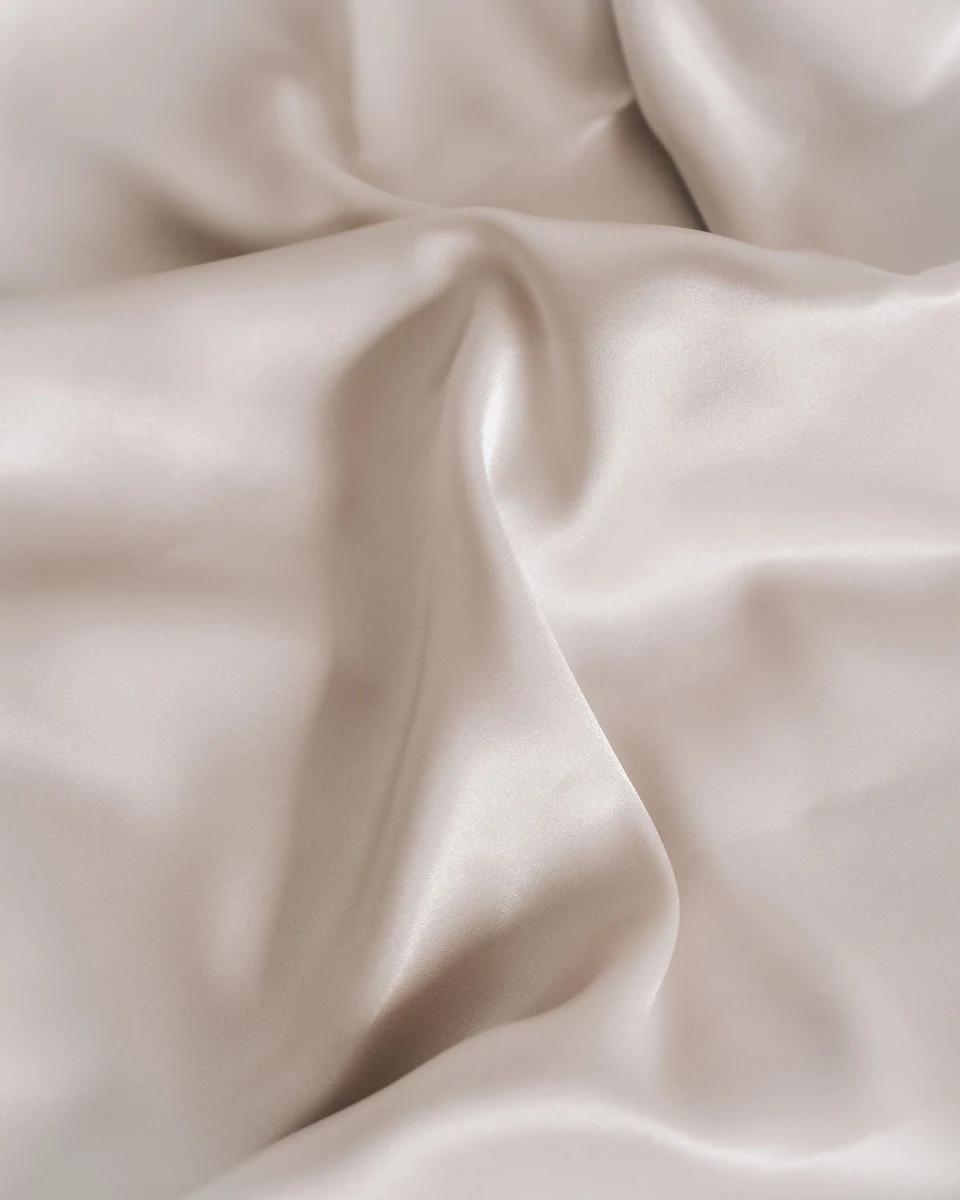 Close view of folds and sheen in light ivory fabric.