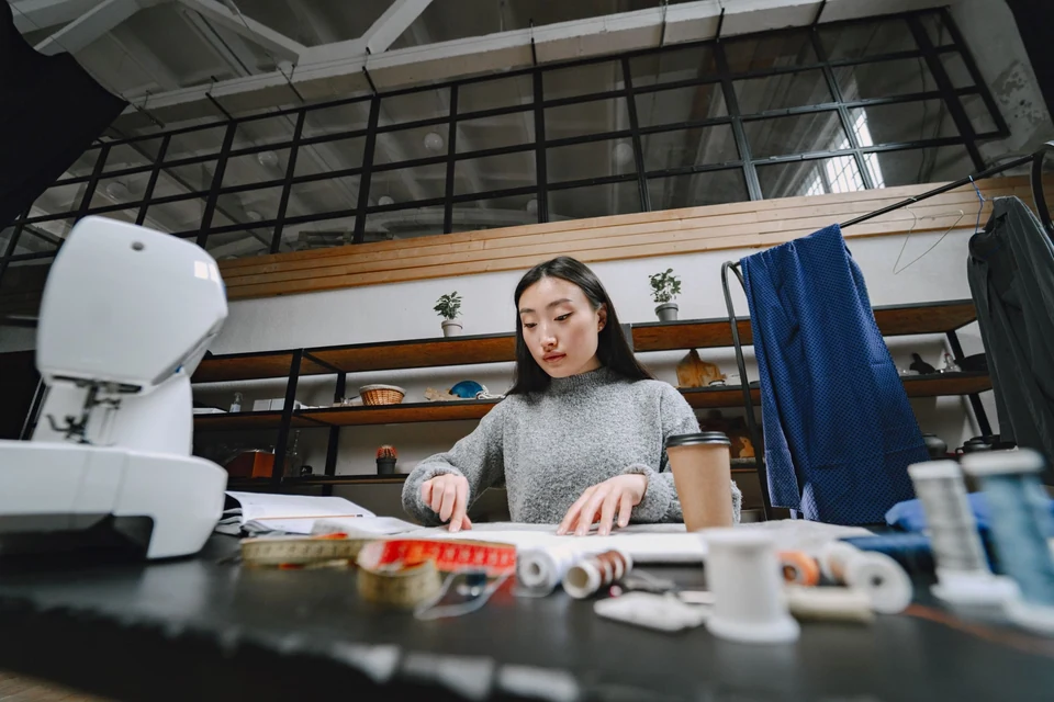 A designer working with fabric at a table in a sewing studio.